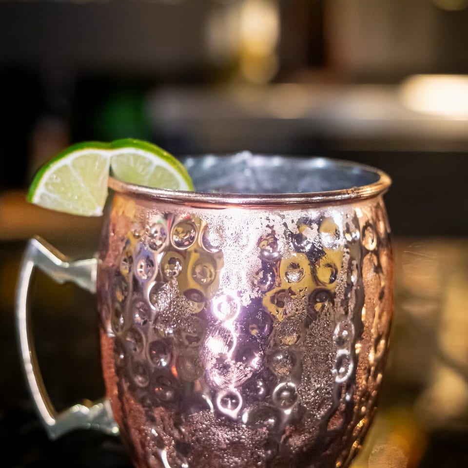 A cold Moscow Mule in a hammered copper mug, garnished with a fresh lime wedge.
